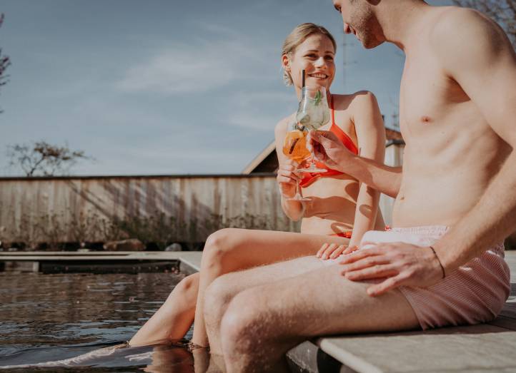 Mann und Frau mit Drink in der Hand am Pool