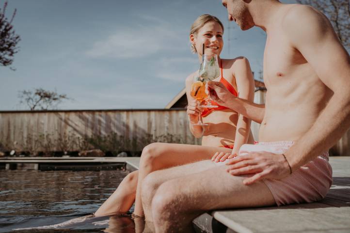 Mann und Frau mit Drink in der Hand am Pool